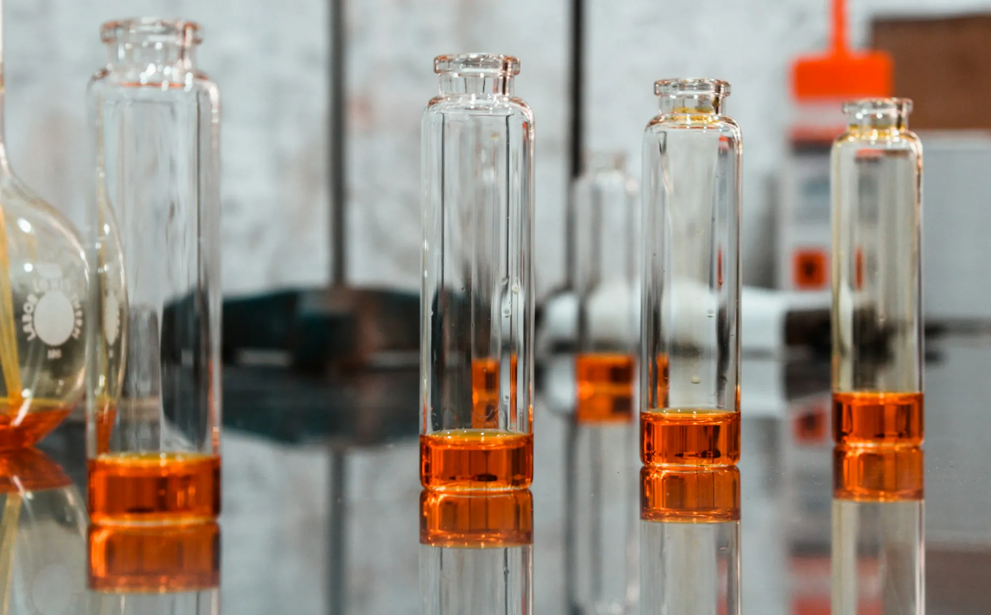 Clear glass bottles and vials on a dark surface, minimal and factual laboratory composition